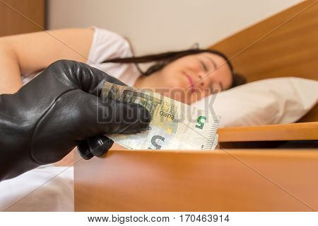 robber steals money of the nightstand while woman sleeps deeply