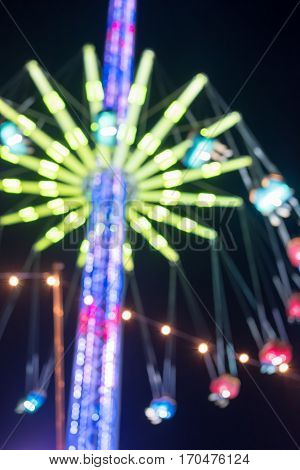 Bokeh blurred image of Merry-go-round chain swing carousel ride in amusement park at night