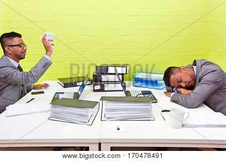 Indian businessman throwing paper at his sleeping twin
