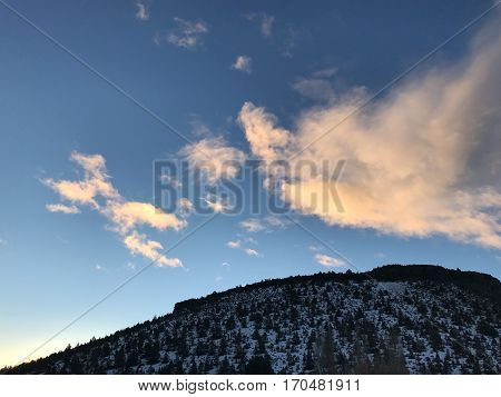 Sunrise over a snow covered butte in Prineville in Central Oregon giving the clouds a red glow against a rich blue sky in the winter.
