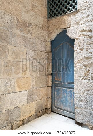 Vintage blue wooden closed door, wooden window with interleaved wooden grid (mashrabiya) and stone bricks wall