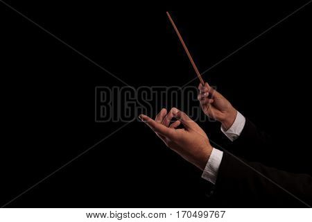 conductor's hands conducting an orchestra on black studio background