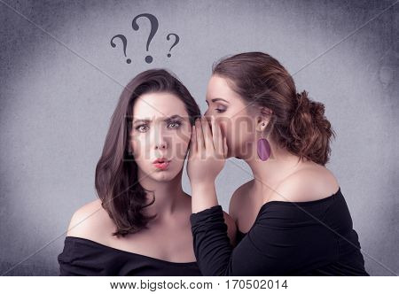 A teenager girl looking confused with drawn question marks above the head, while a girlfriend whispers something in her ear concept.