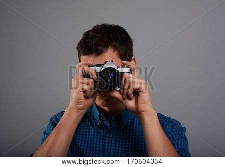 Close up high detailed portrait of tourist who making photo with vintage camera. Handsome man portrait in studio. Touristic concept on neutral grey background.
