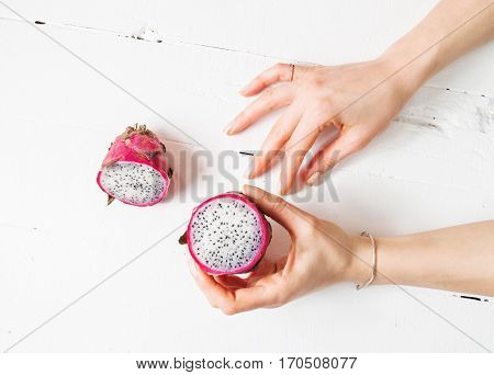 Female hands and Juicy pink pitaya on wooden table.