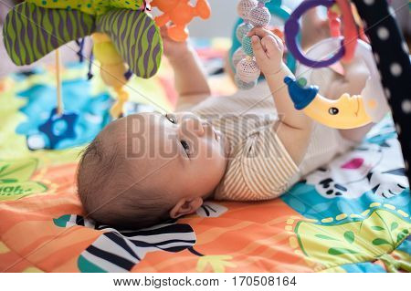 baby lying on Developing rug. playing in Mobile. educational toys. Sweet child Crawling And Playing With Toys On Carpet