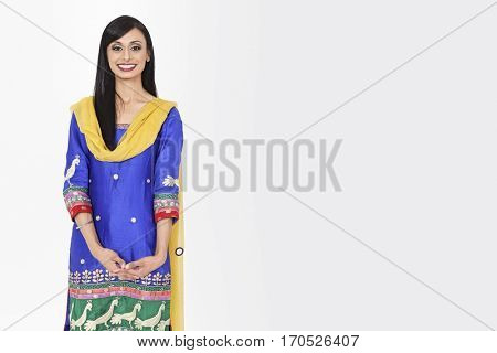 Portrait of an attractive Indian female in traditional wear standing over gray background