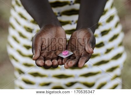 African child hands holding medicine pill outdoors.