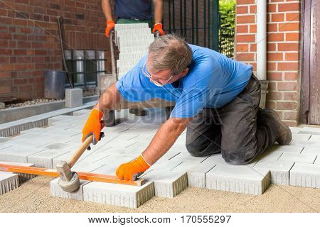 Builder Levelling Paving Stones As He Lays Them