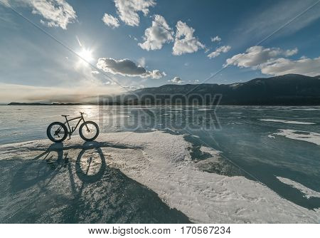 Fatbike also called fat bike or fat-tire bike - Cycling on large tire wheels. Cyclist goes to his bike on the frozen lake. Picture taken in HDR mode.
