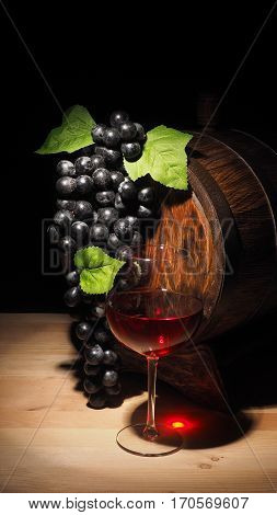 Glass Of Red Wine And Barrel On Wooden Table