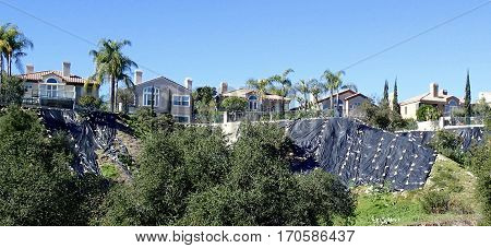A neighborhood tries to save their homes from hill erosion with black tarps