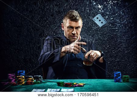 Excited gambling man throwing playing cards on a game table in a casino. Gambling, playing cards and roulette.