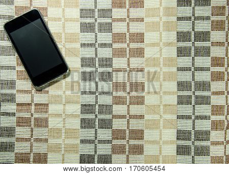 Black Smart Phone on The Tablecloths Background. Use for Texture and Wallpaper.