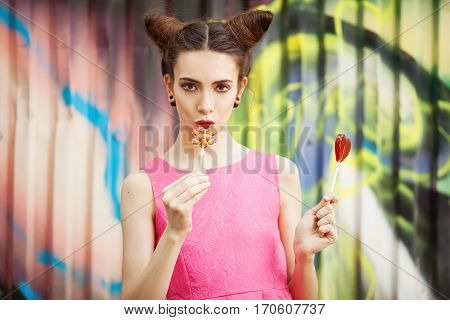 Young girl in a pink dress with candy on a decorated background of graffiti wall
