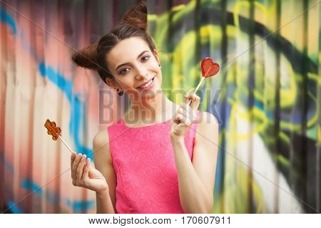 Young girl in a pink dress with candy on a decorated background of graffiti wall