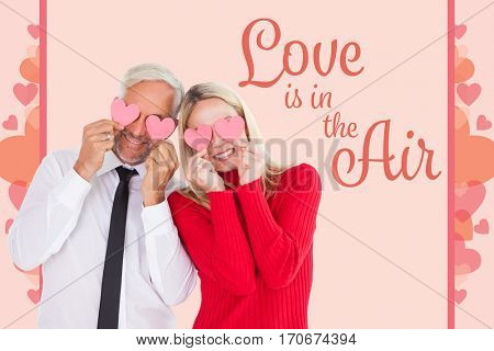 Silly couple holding hearts over their eyes