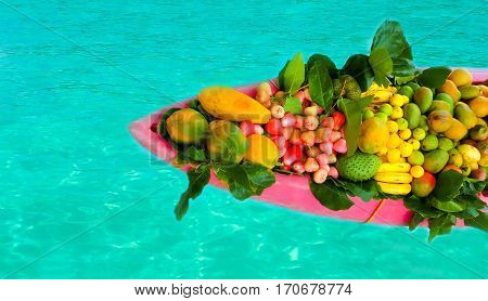 The exotic tropical fruits on the boat canoe against blue water
