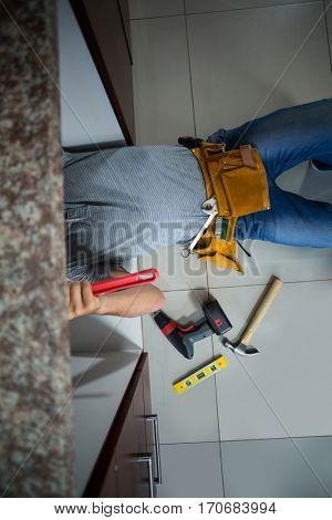 Low section of man working while lying in kitchen