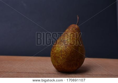 Pear on a wooden board. Pear on a dark background. Fresh fruit. Space for text.