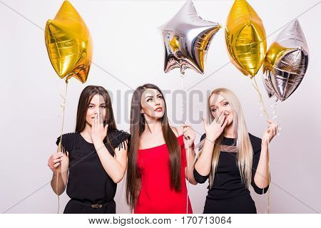 Three Lovely Young Women Standing And Holding Star Shaped Balloons Over White