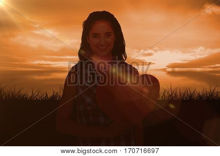Portrait of smiling woman holding heart card against a couldy day