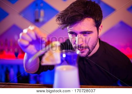 Bartender arranging fruits on cocktail glass at bar counter