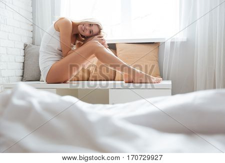 Beauty woman sitting near the window and looking at camera