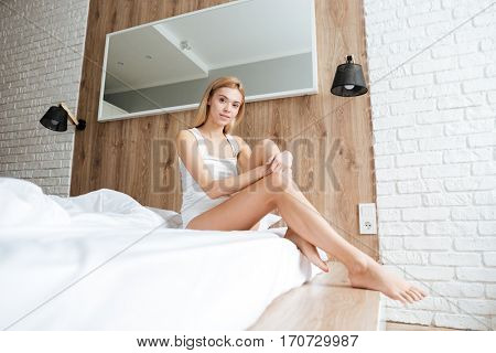 Side view of woman sitting on bed in the bedroom