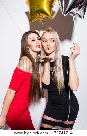 Two Smiling Cute Young Women  With Balloons Send Kisses.