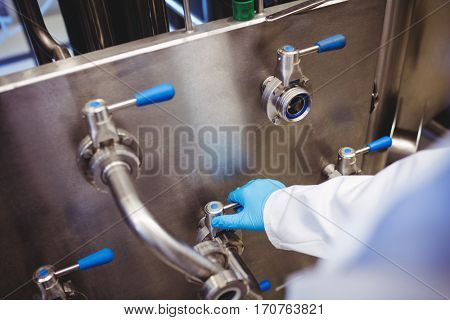 High angle view of manufacturer adusting pipe at brewery