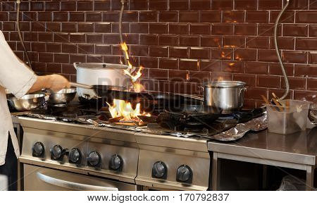Chef is making flambe dish in restaurant kitchen