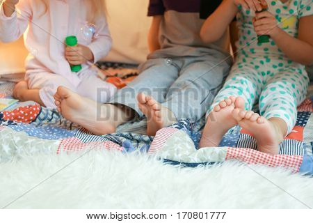 Cute little children blowing soap bubbles in hovel, closeup