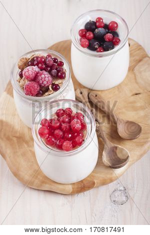 Homemade yogurt with frozen berries red currants black currants raspberries and cranberries in three banks