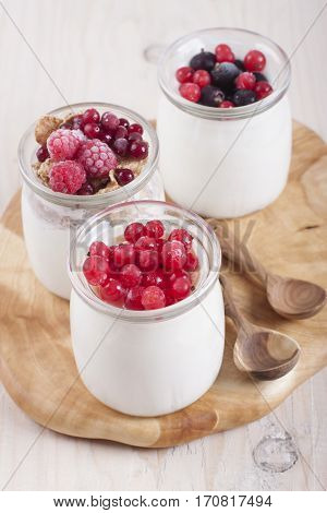 Homemade yogurt with frozen berries red currants black currants raspberries and cranberries in three banks