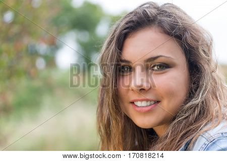 Portrait of smiling longhair brunette teenage girl outdoors closeup.