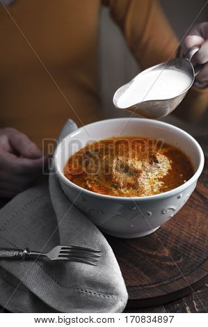 Butter chicken sauce-boat with cream and a woman at the table vertical