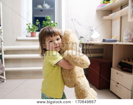 child hugging toy teddy bear indoor in her room happy childhood concept smiling cute baby girl playing with toy