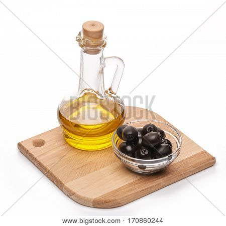 Glass cruet with Extra virgin olive oil, canned black olives in bowl stand on a wooden cutting board on a white background.