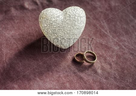 Love, Wedding And Valentine`s Day Concept. Beautiful Golden Wedding Rings And Glass Heart Selective