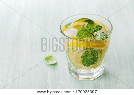 Soda water or mineral water with limes, lemons, ice and mint leaves on light blue background. Can be used for detox diet.