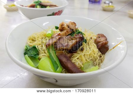 Char Siew Barbecue Pork Wanton Noodles with green vegetable dried on table version closeup macro