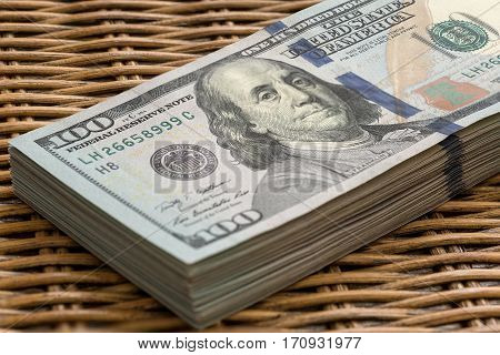 Stack of United States of America USD 100 One Hundred Dollars Federal Reserve Note in a Pile on Wicker Background