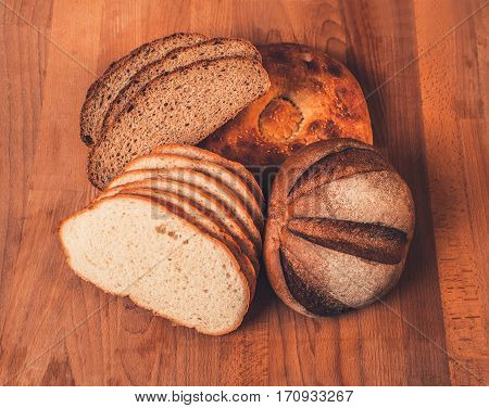 Assorted white and rye bread on a wooden table. Top view. Fresh fragrant crispy sliced bread. Loaf of white and rye bread slices on cutting board closeup. Home-made bread on a wooden background.