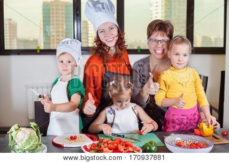 Three cute kids are preparing a salad in the kitchen. Healthy eating