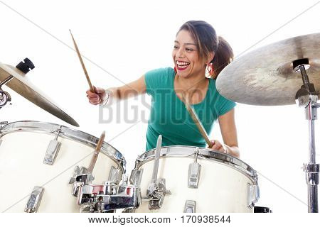 brunette brazilian woman has fun playing the drums in studio against white background