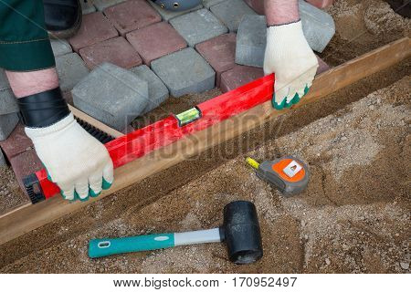 Mason worker making sidewalk pavement with stone blocks