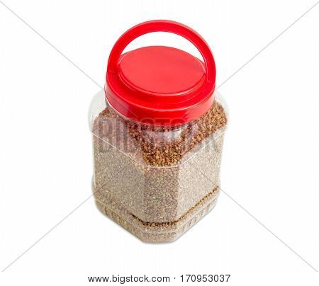 Buckwheat groats peeled from the husk in the transparent plastic container with a red cover on a light background