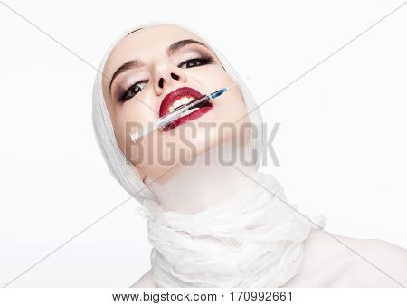 Beautiful model holding syringe in her lips for plastic surgery contept on white background