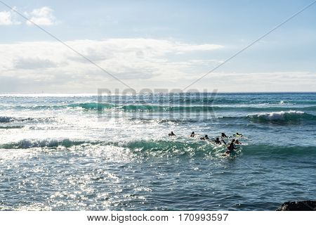 Surf school - several surfboarding students headed into an ocean swell on Tenerife Spain
